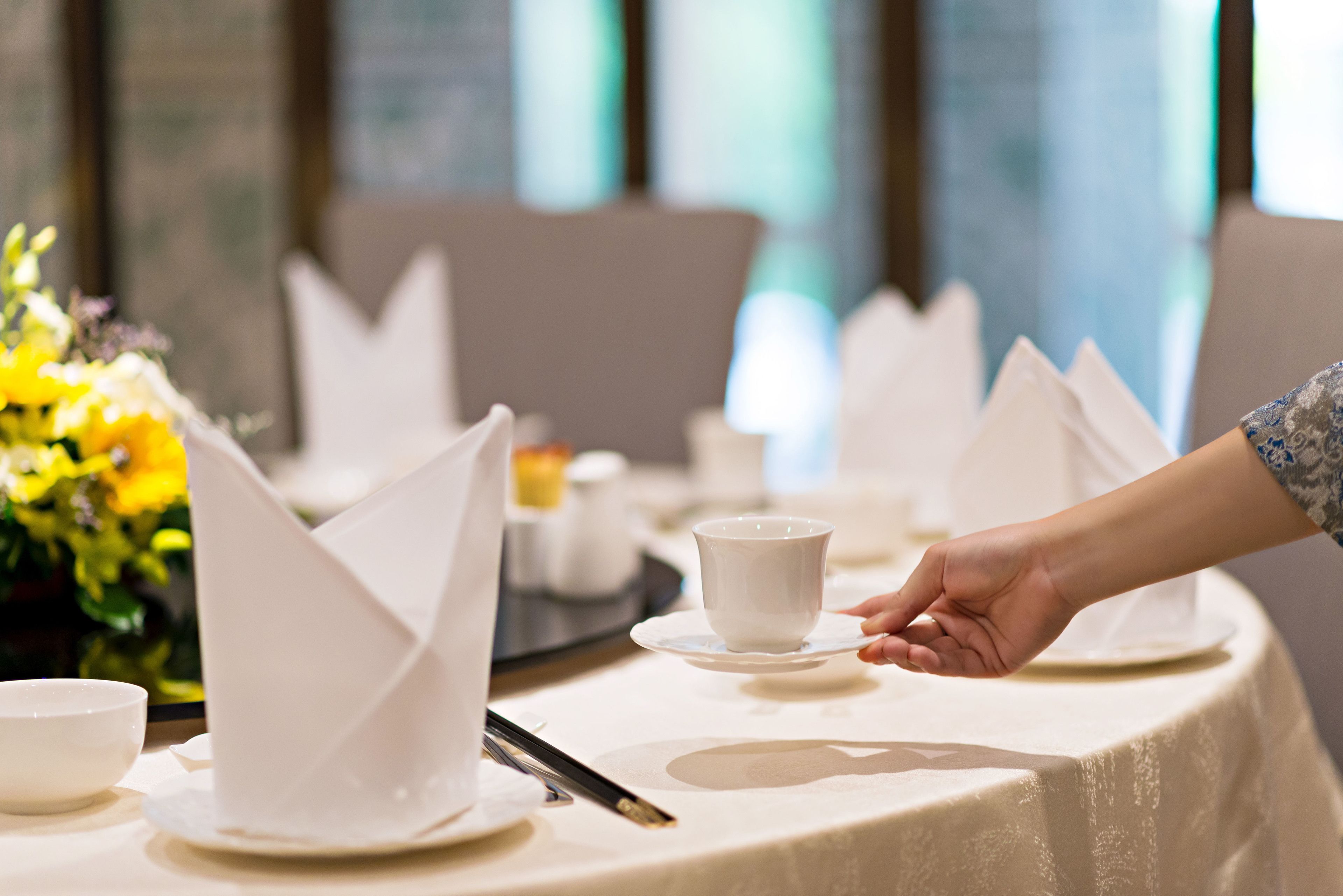 Una mesa servida para una comida, con servilletas blancas, una taza y un tazón.