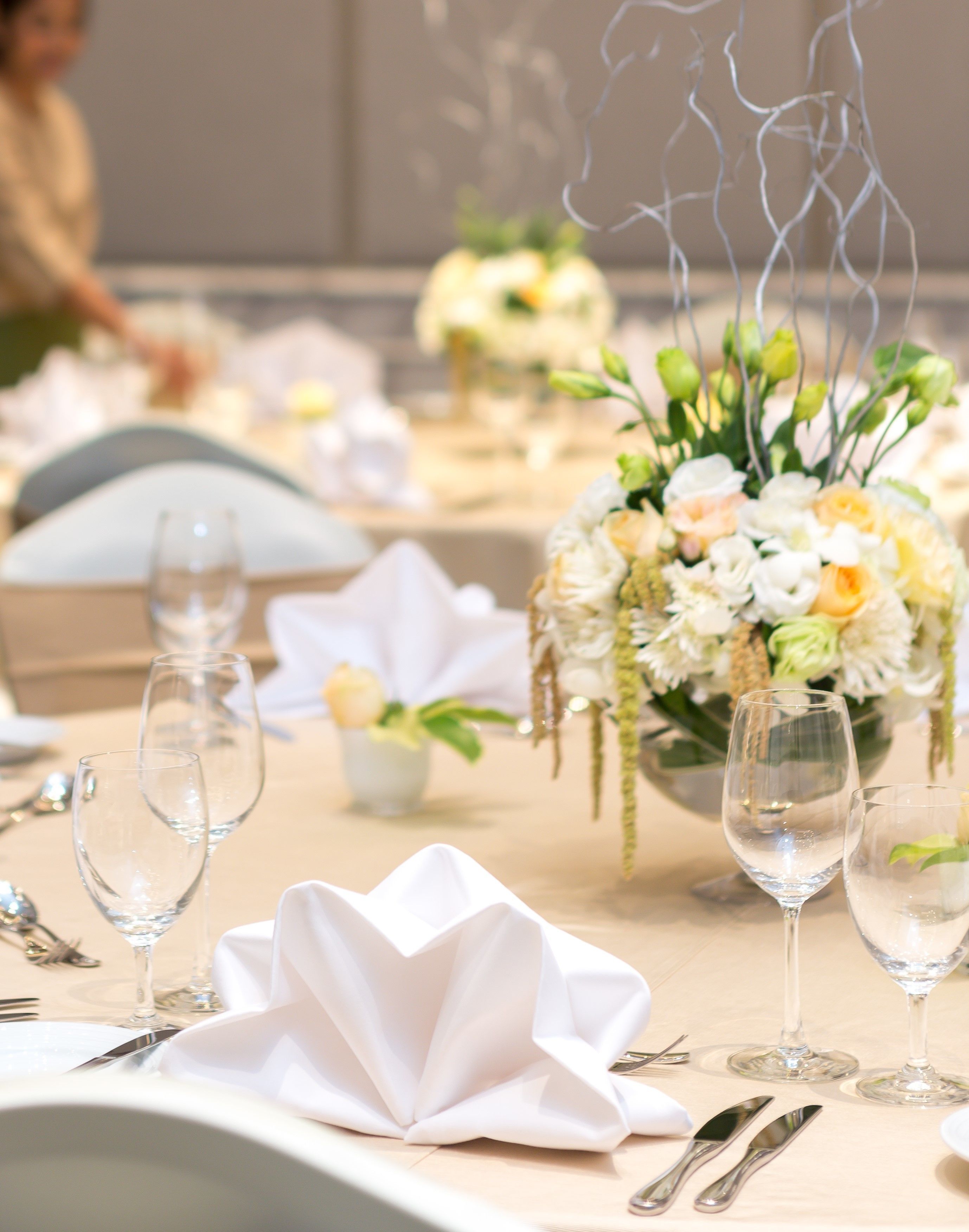 Een gedekte tafel voor een formeel evenement, met witte tafelkleden, helder servies en een bloemstuk als decoratie.