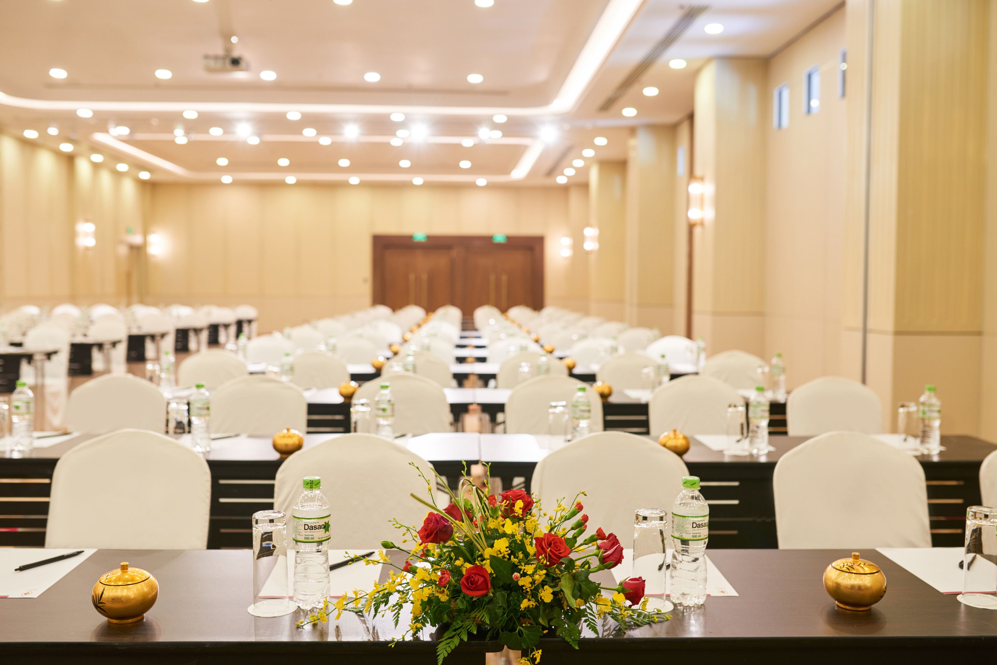 A conference room with rows of tables, chairs, and water bottles.