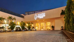 Entrada del Eastin Grand Hotel Saigon con un camino pavimentado, coches estacionados y plantas en macetas.