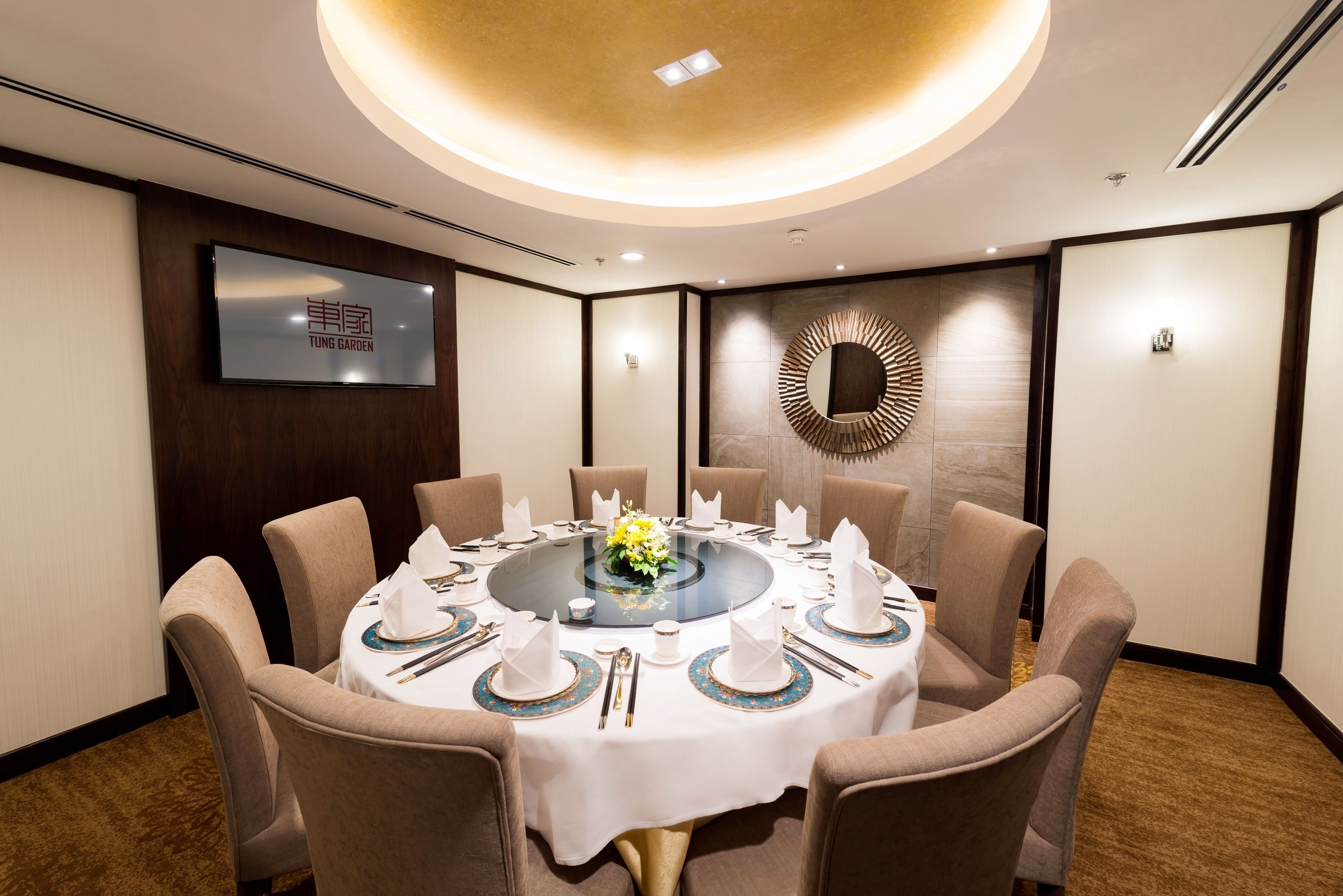 A conference room with a round table set for eight, surrounded by beige chairs.