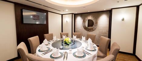 A conference room with a round table set for eight, surrounded by beige chairs.