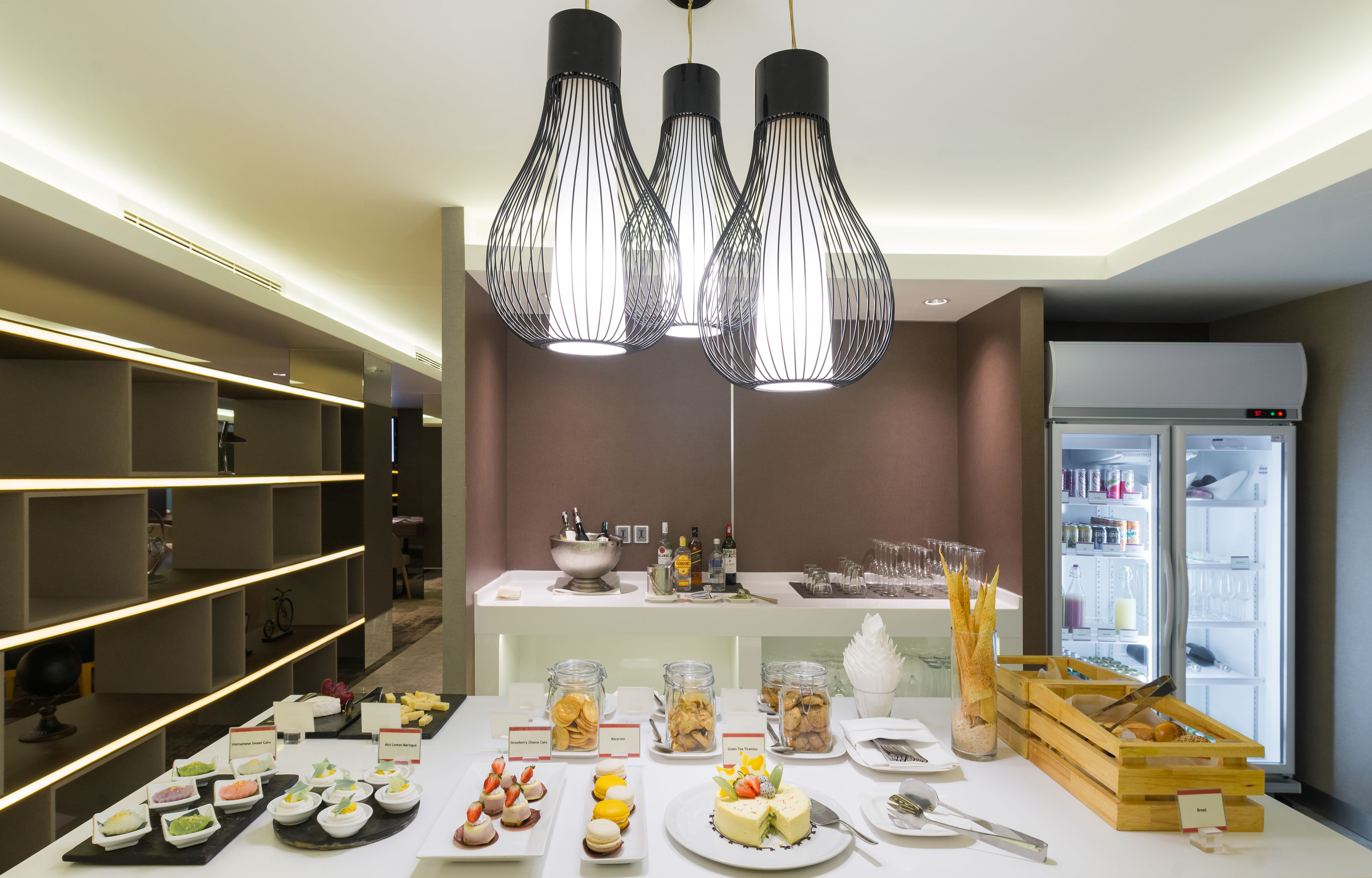 A buffet setup with various food items and a refrigerator in the background.