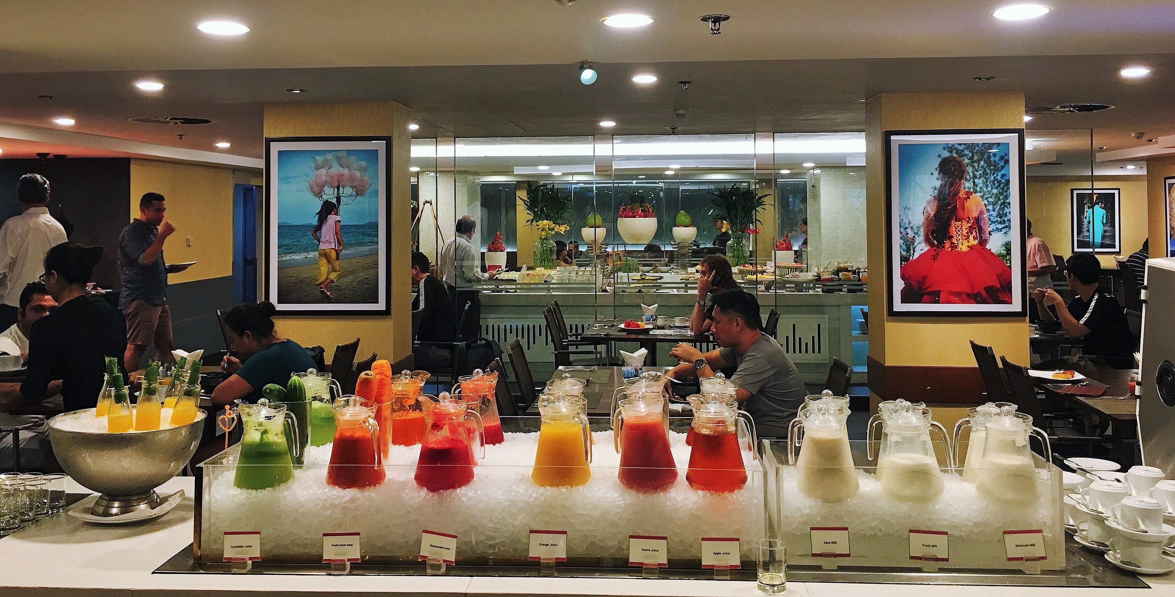 A buffet area with various colorful beverages and a kitchen in the background.