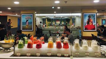 A buffet area with various colorful beverages and a kitchen in the background.