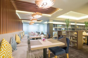 A modern restaurant with a long counter, multiple tables, and chairs.