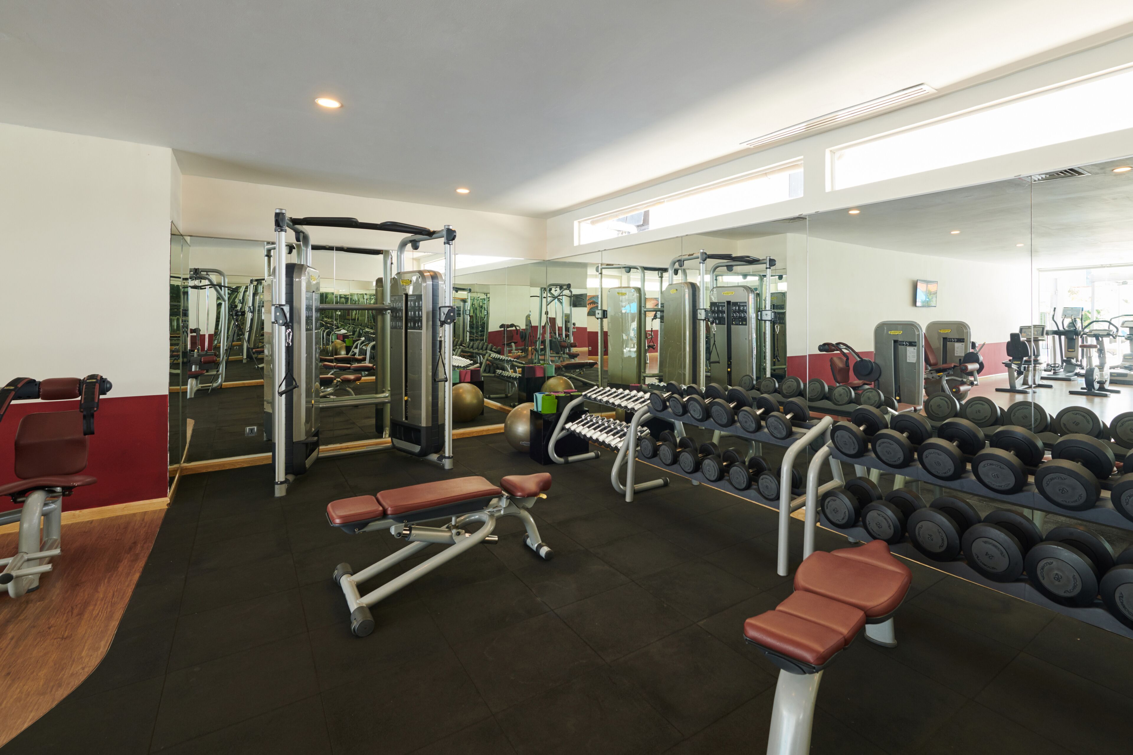 A gym with various exercise equipment, including benches, dumbbells, and weight machines.