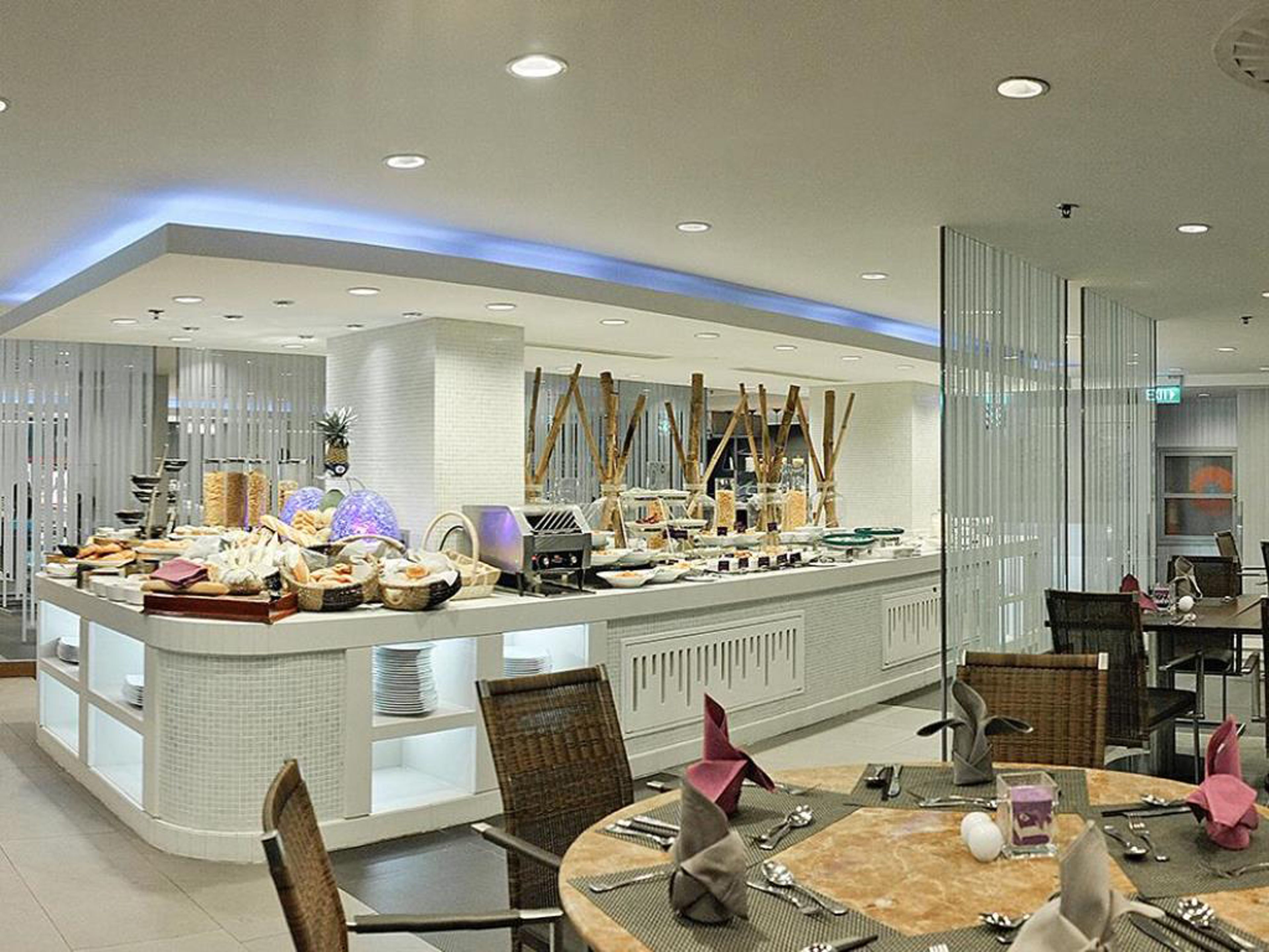 A modern hotel dining area with a central buffet, seating arrangements, and a contemporary design.