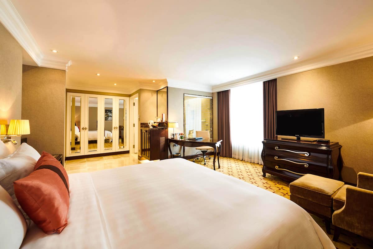Una habitación de hotel con una cama grande, un escritorio, un televisor y un armario.