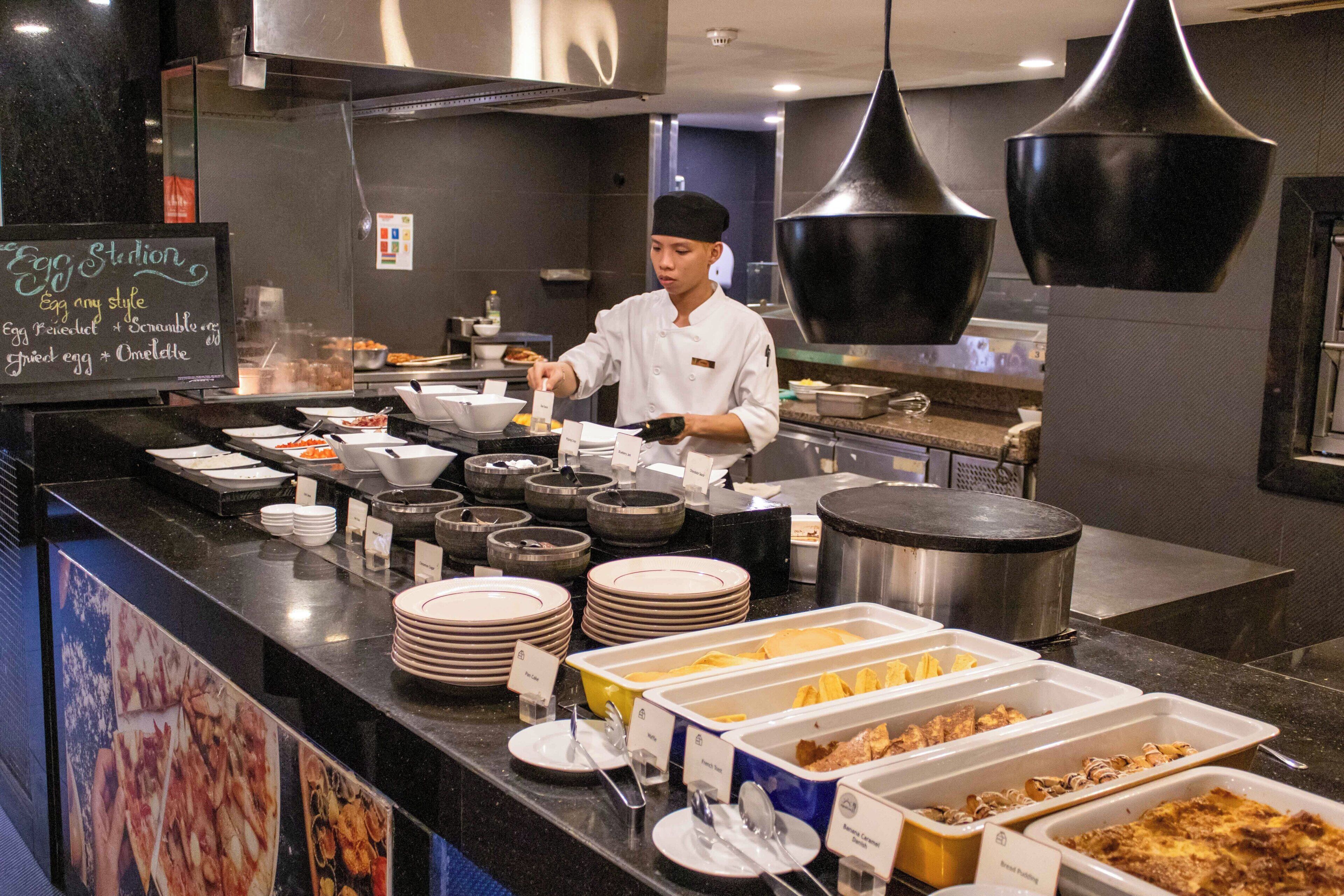 A buffet setup with various food items and a chef serving.