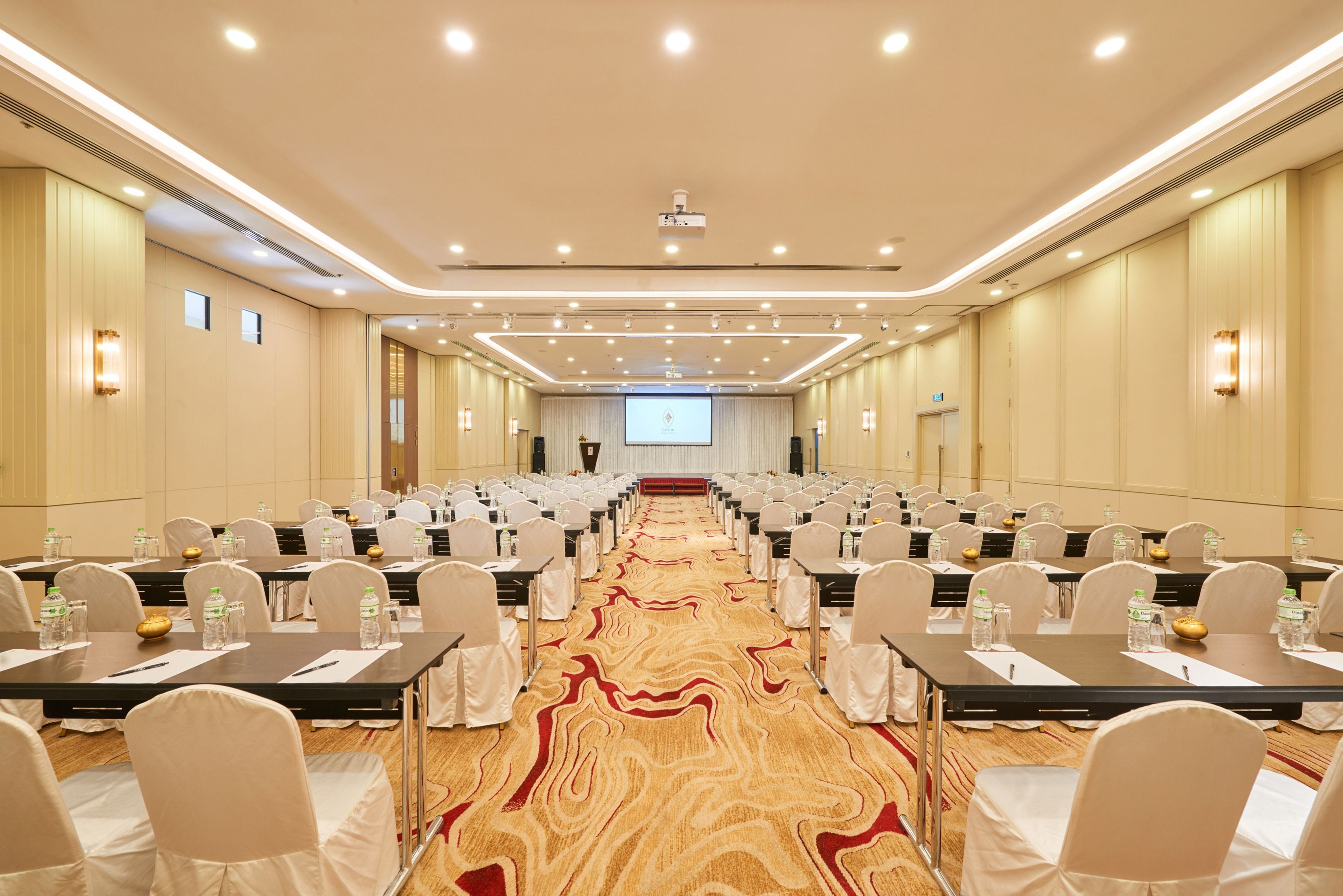 A conference room with rows of tables and chairs, equipped with water bottles and nameplates.