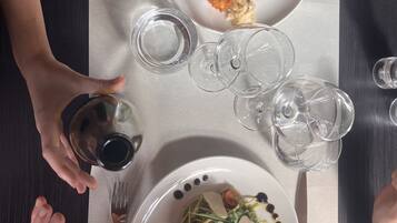 A dining table with plates of food, wine glasses, and cutlery.