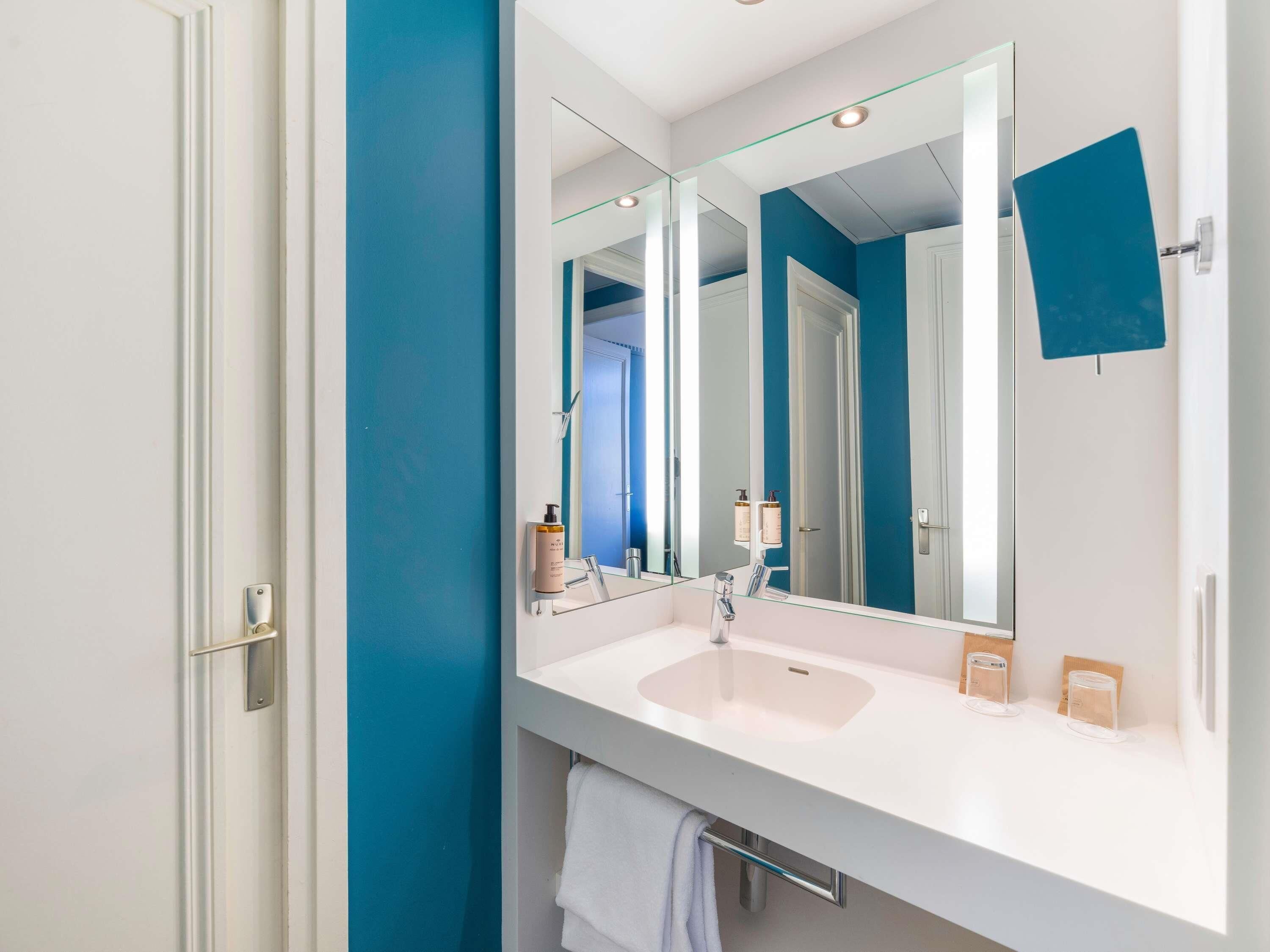 A bathroom with a white sink, a large mirror, and a towel rack.