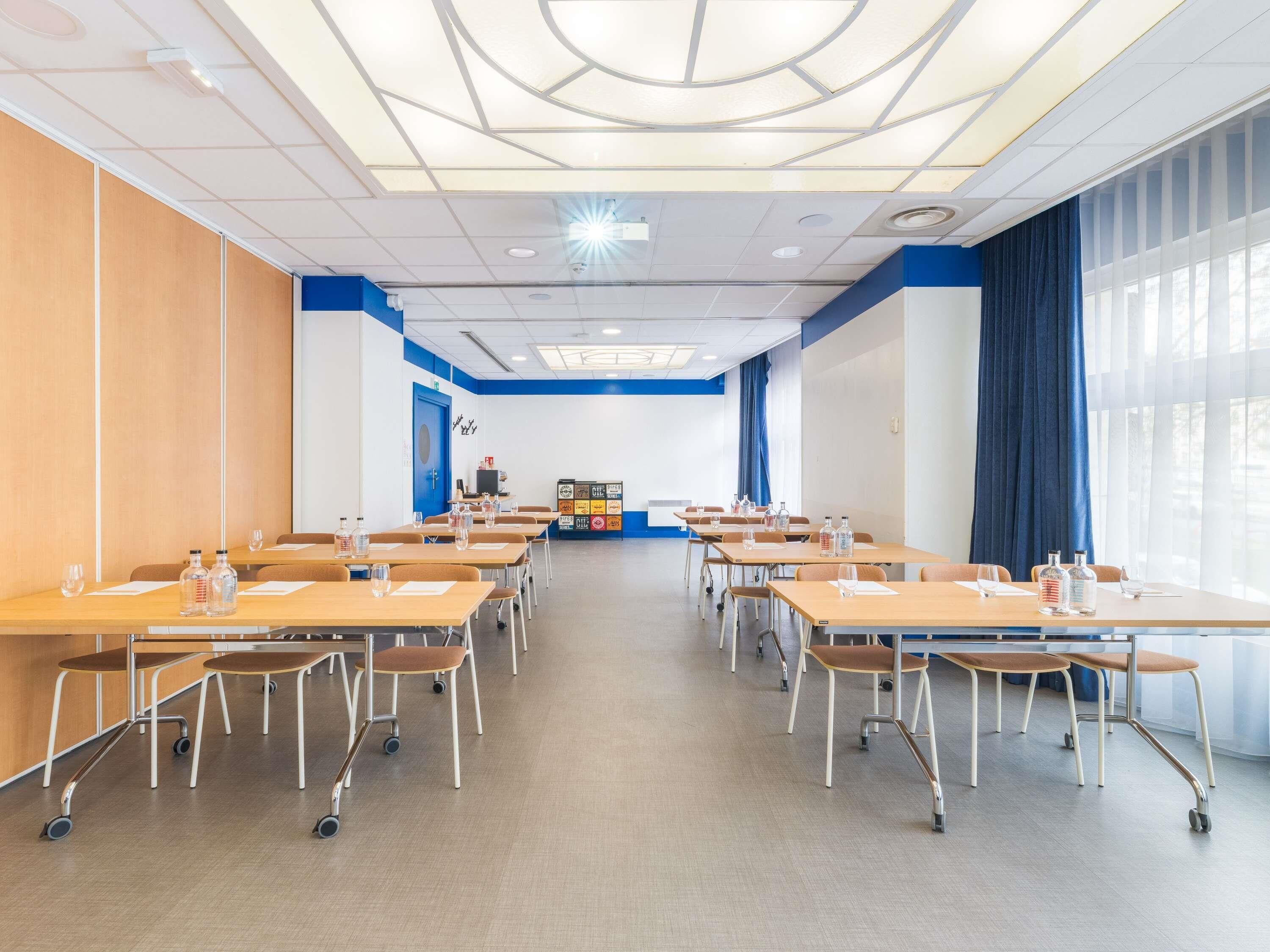 A conference room with tables, chairs, and a presentation screen.