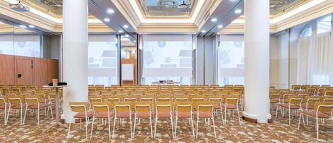 A conference room with rows of chairs, a podium, and a large screen.