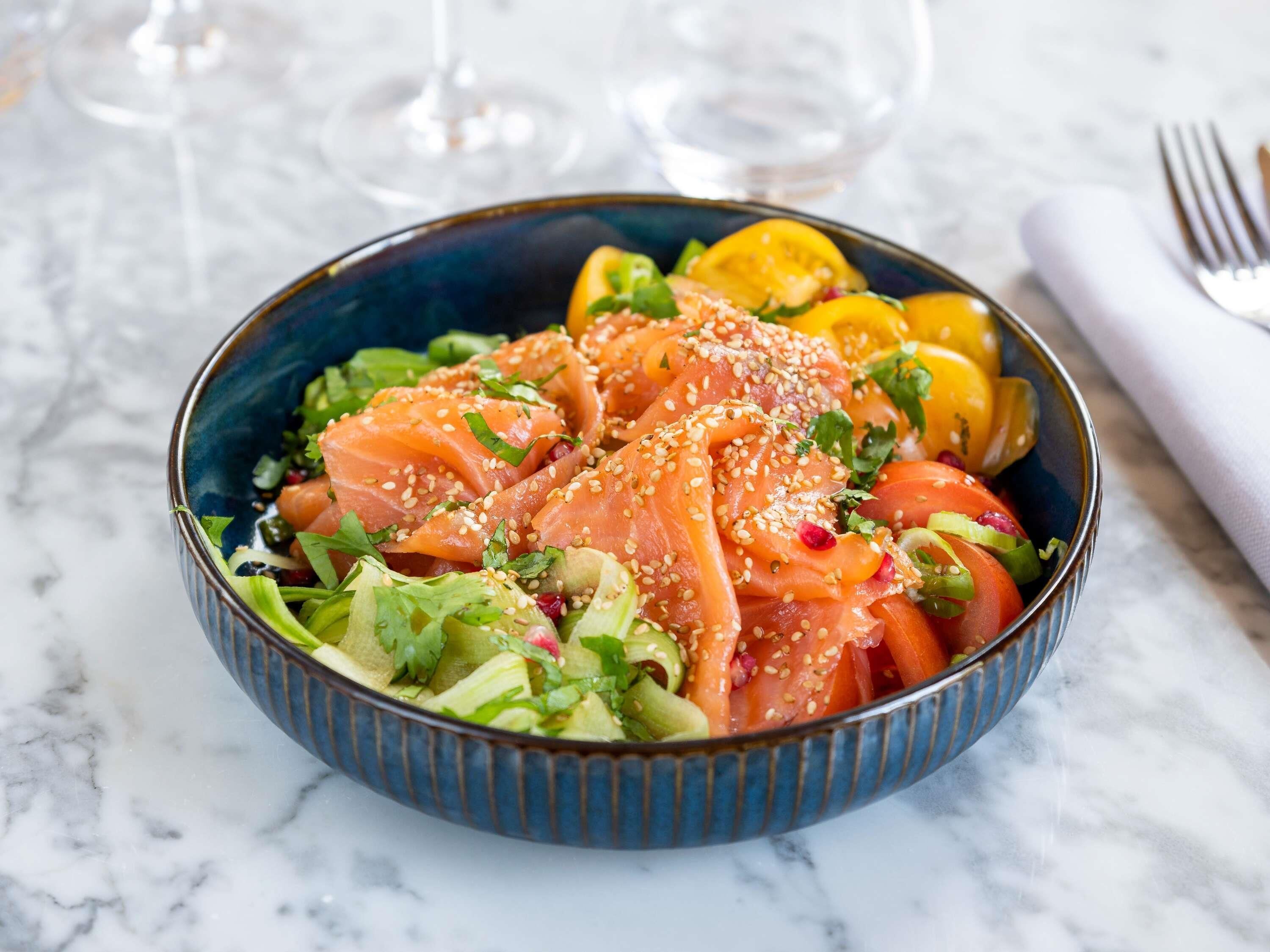 Een schaal eten met zalm, groenten en sesamzaadjes.