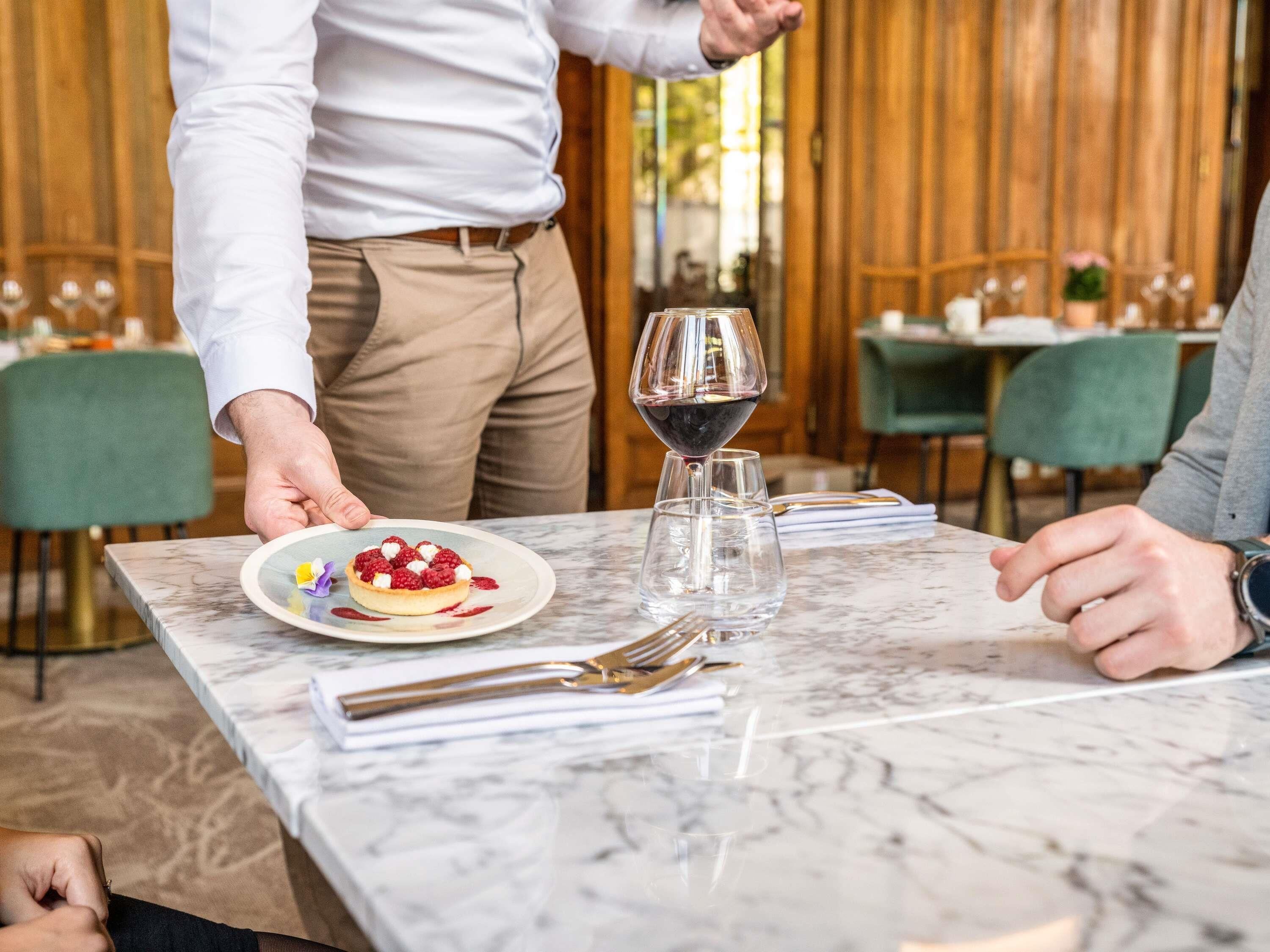 A marble table with a dessert plate, a wine glass, and cutlery.
