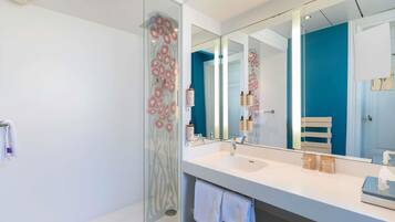 A modern bathroom with a glass shower enclosure, a large mirror, and a white vanity with a sink.