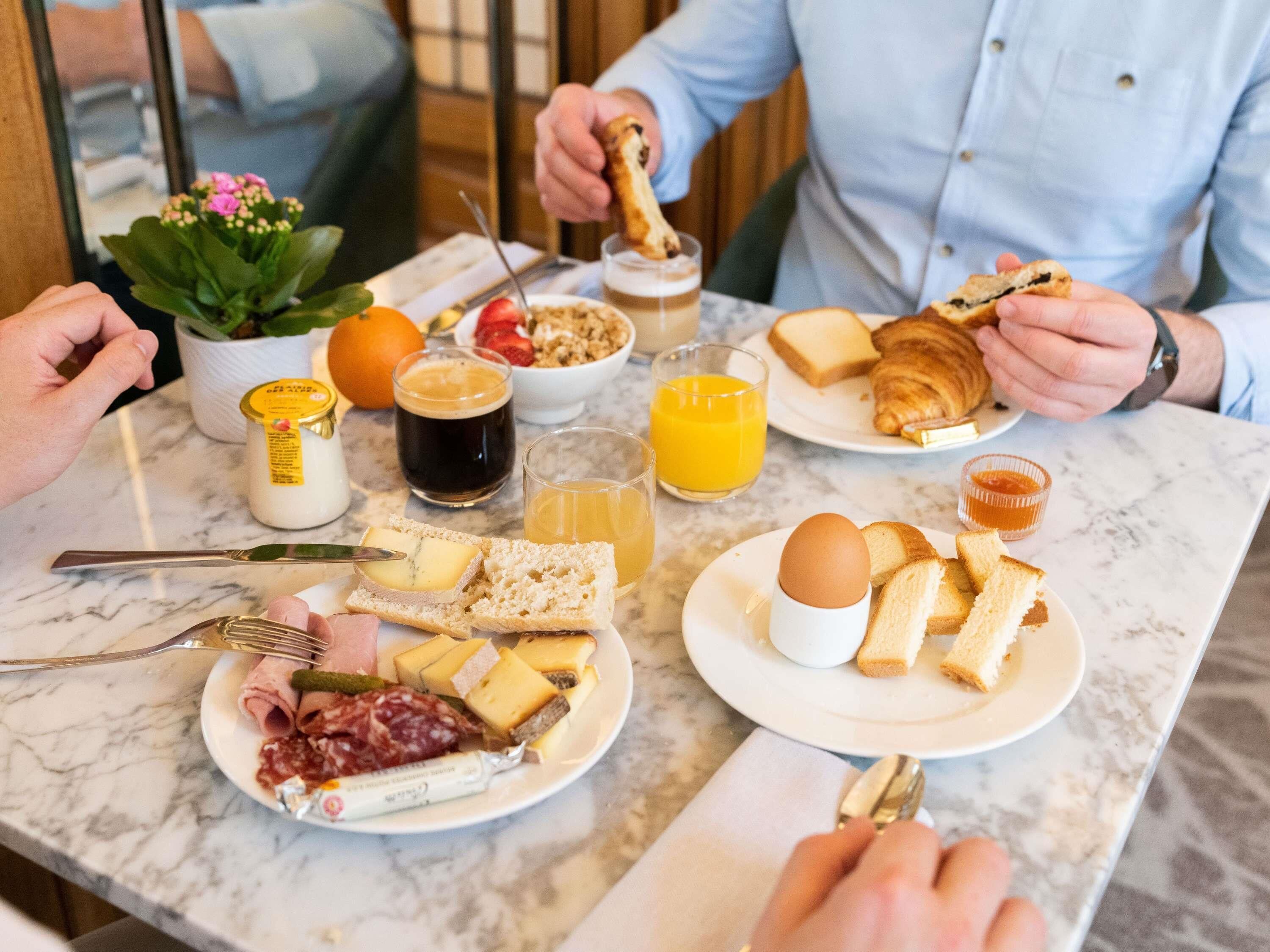 A breakfast setting with various food items and drinks on a marble table.