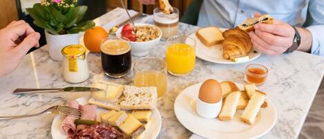 A breakfast setting with various food items and drinks on a marble table.