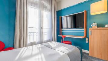 A hotel room with a bed, a TV, a desk, and a chair.