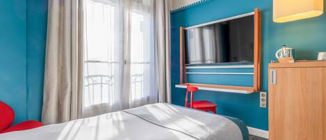 Una habitación de hotel con cama, televisión, escritorio y silla.