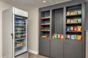 A vending machine stocked with various beverages and snacks, including chips and sea salt snacks. - City Express by Marriott I-10 West Energy Corridor (Houston)