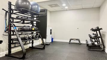 A gym with exercise equipment including a pull-up bar, kettlebells, and a step platform.