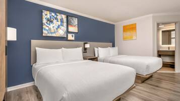 A hotel room with two beds, a nightstand, a lamp, and wall art.