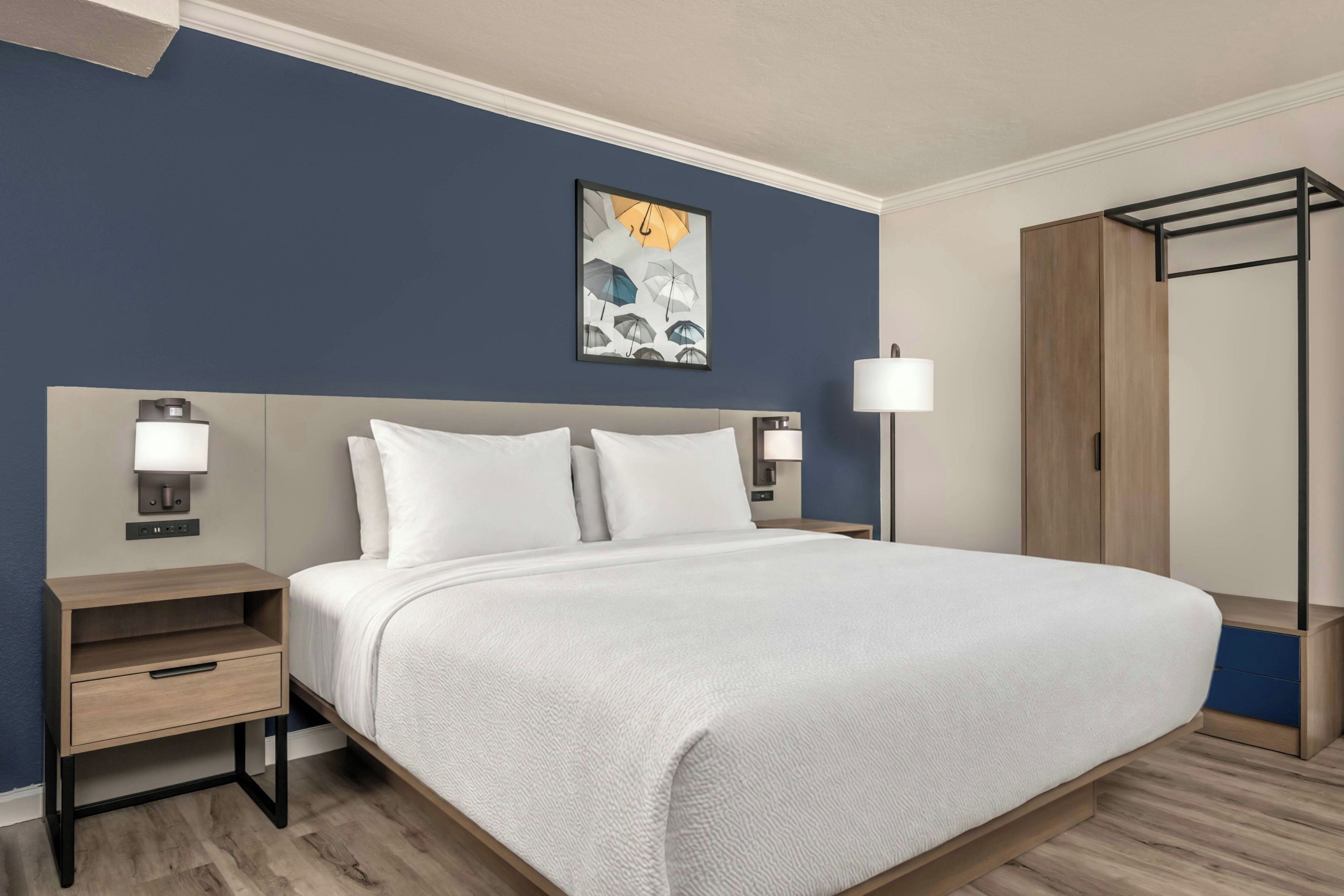 Una camera d'albergo con un letto, comodini, un armadio e un quadro appeso al muro.