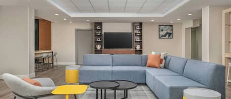 A modern living room with a sectional sofa, a coffee table, and a TV mounted on the wall.