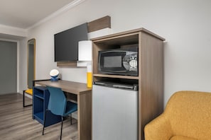 A compact kitchenette with a microwave, a small refrigerator, a table, and a chair. - City Express by Marriott I-10 West Energy Corridor (Houston)