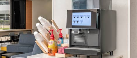 A coffee machine with a digital display and a menu, surrounded by disposable cups and coffee-related items on a counter.