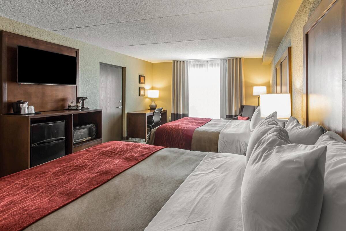 Una habitación de hotel con dos camas, televisión, escritorio y minibar.
