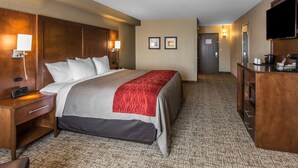 Une chambre d’hôtel dotée d’un grand lit, de tables de chevet, d’un bureau, d’un téléviseur à écran plat et d’une porte donnant sur une autre pièce.