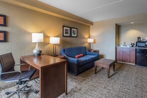 Une chambre d’hôtel équipée d’un bureau, d’une chaise, d’un canapé et d’une kitchenette.
