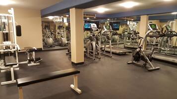 A gym with various exercise equipment, including treadmills, stationary bikes, and weight machines.