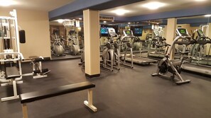 Un gimnasio con diferentes equipos de ejercicio, incluyendo cintas de correr, bicicletas estáticas y máquinas de pesas.