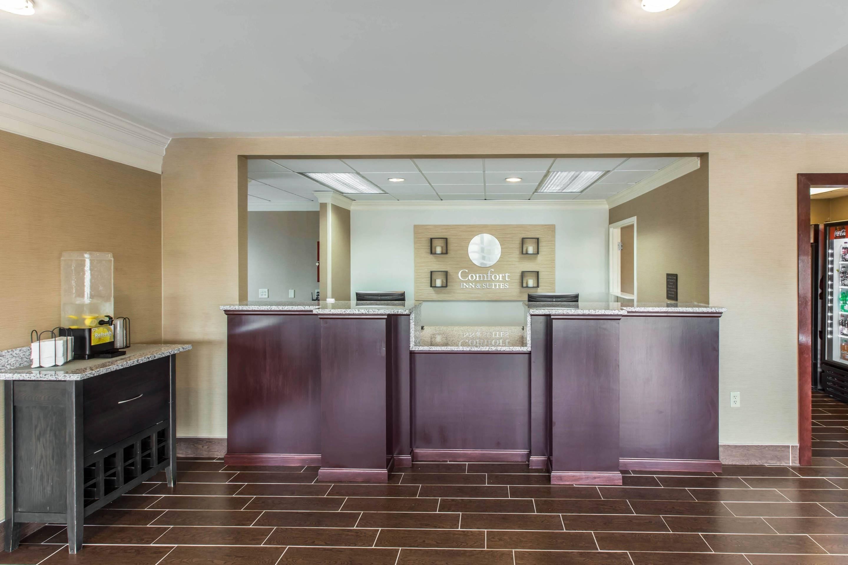 A reception area with a counter, a refreshment station, and a sign for Comfort Inn & Suites.