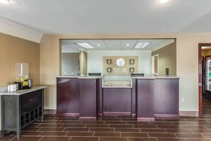 Un espace d’accueil comprenant un comptoir, un coin boissons et un panneau indiquant « Comfort Inn & Suites ».