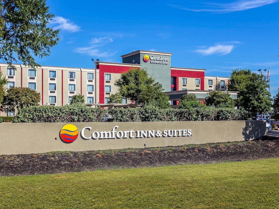 A Comfort Inn & Suites hotel with a large sign, multiple floors, and a well-maintained lawn.