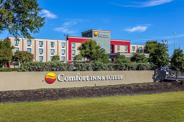 A Comfort Inn & Suites hotel with a large sign, multiple floors, and a well-maintained lawn.
