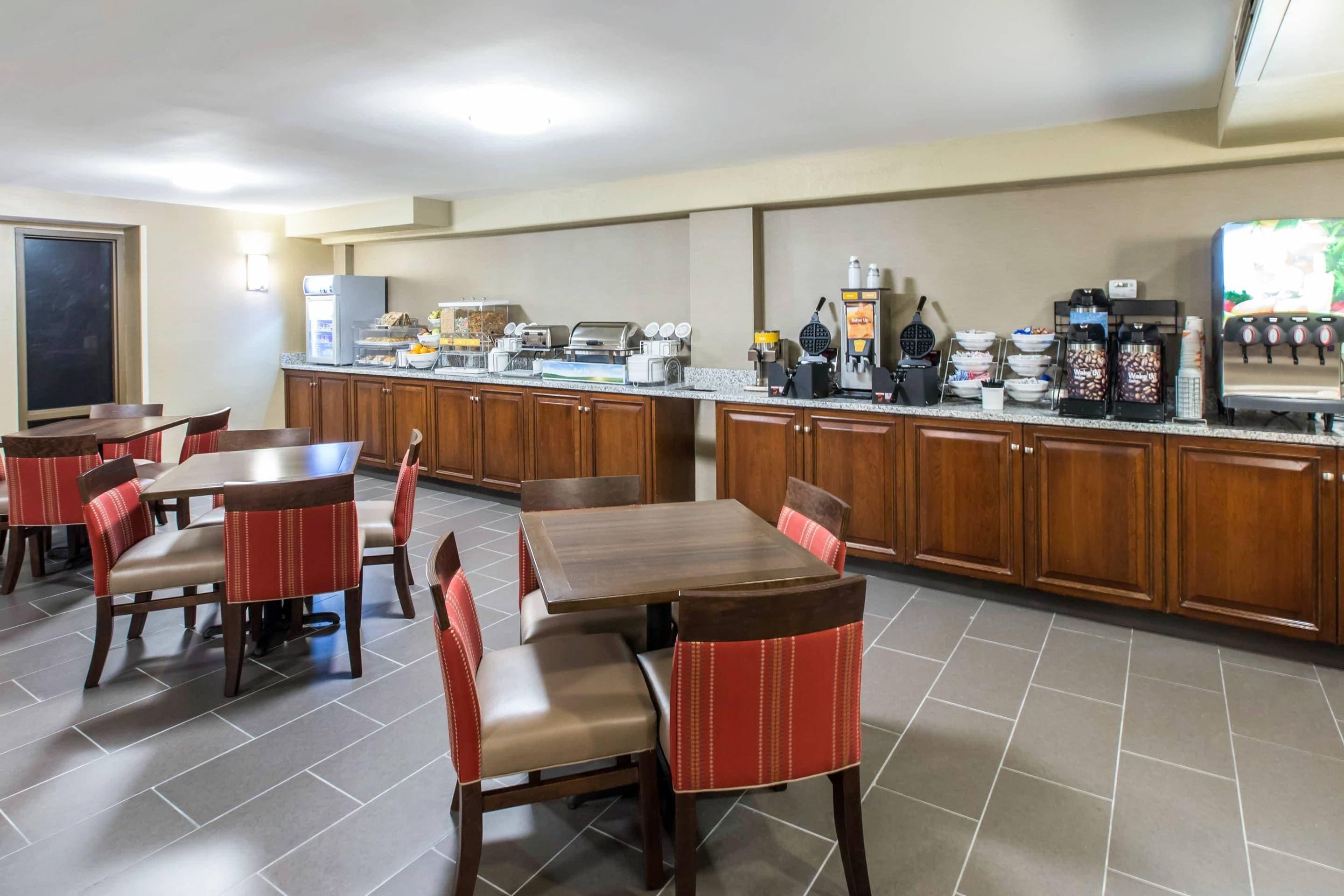 A breakfast area with a buffet, coffee machines, and seating.