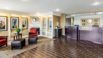 A hotel lobby with a reception desk, seating area, and a fireplace.