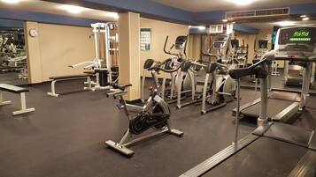 A gym with various exercise equipment including treadmills, stationary bikes, and weight machines.