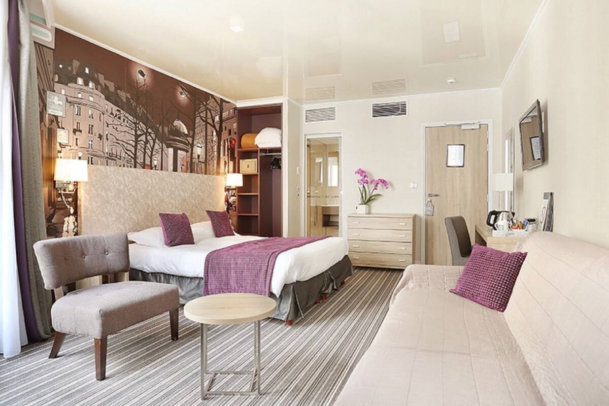 Una habitación de hotel con una cama grande, un sofá, una silla, una mesita y un aparador.