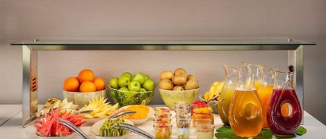 Una mesa de buffet con frutas, verduras y bebidas diversas.