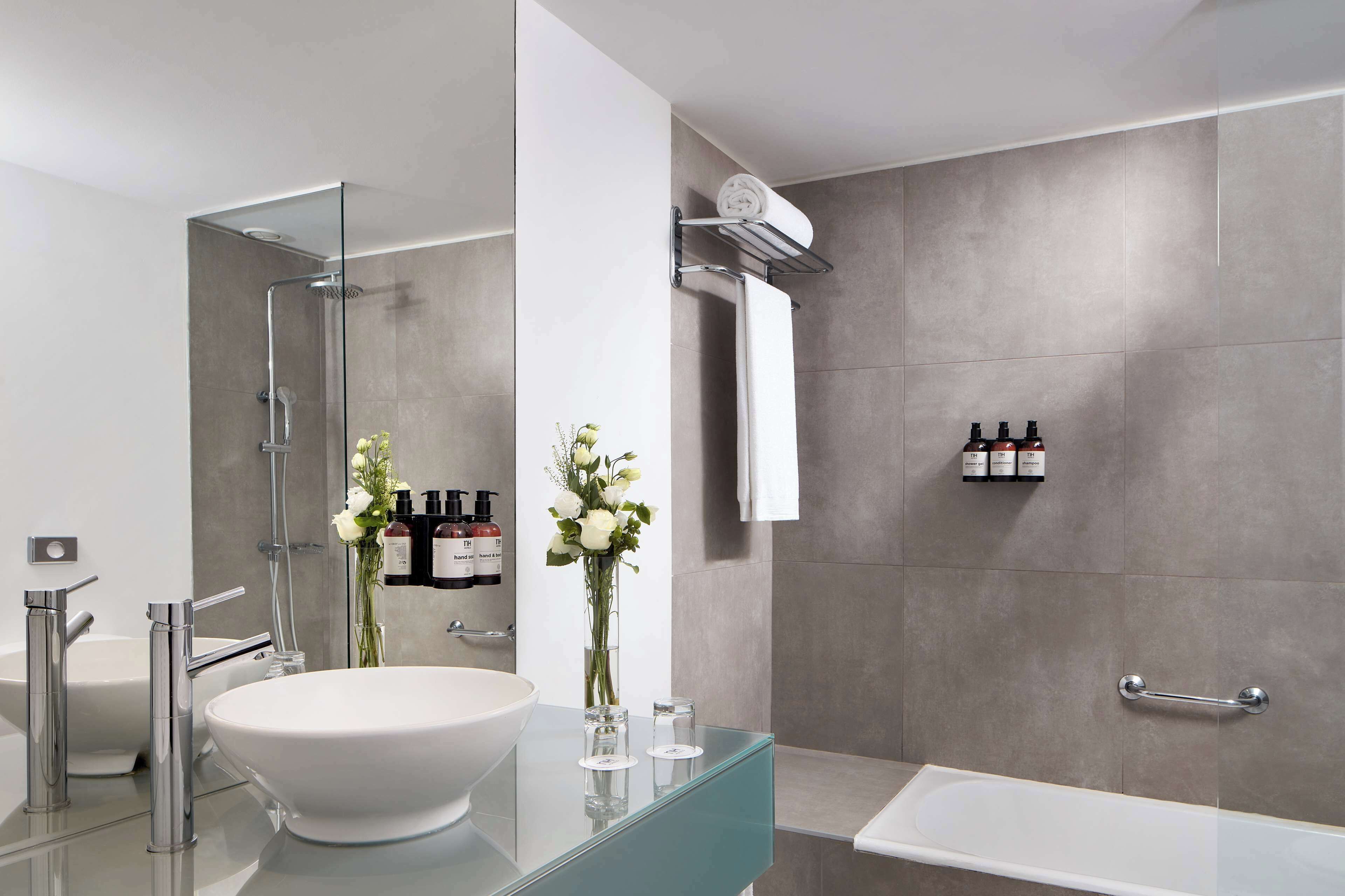 Uma casa de banho moderna com uma grande lavatório branco, toucador de vidro, chuveiro com porta de vidro e uma banheira.