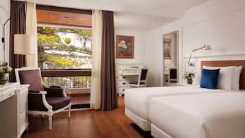 Una habitación de hotel con una cama grande, un escritorio con silla, un aparador y una ventana con cortinas.