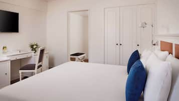 Una habitación de hotel con una cama grande, un escritorio con una silla, un televisor y un armario.